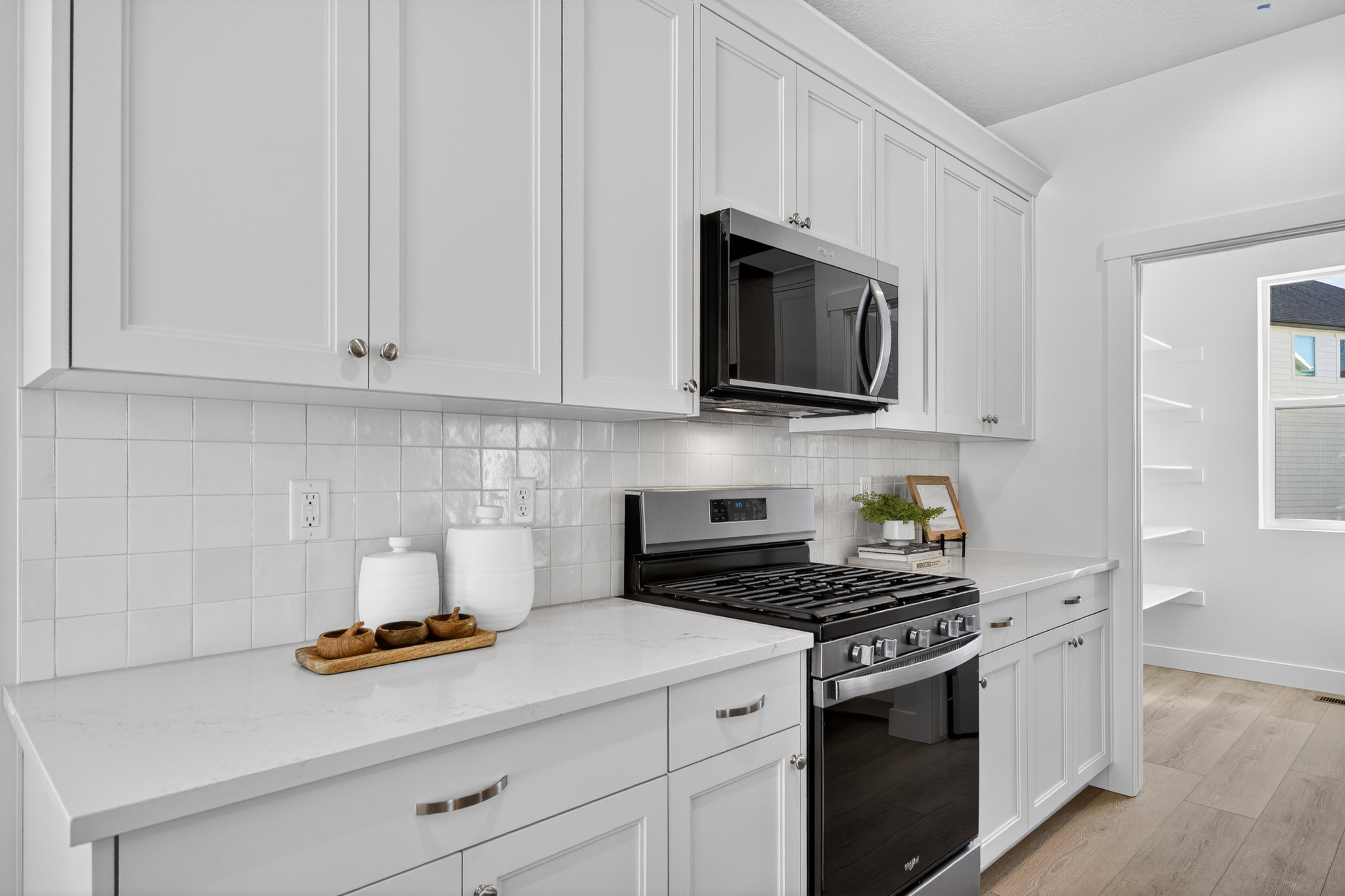 Kitchen featuring white shaker-style cabinetry, stainless steel appliances, a white tile backsplash, and light-toned countertops