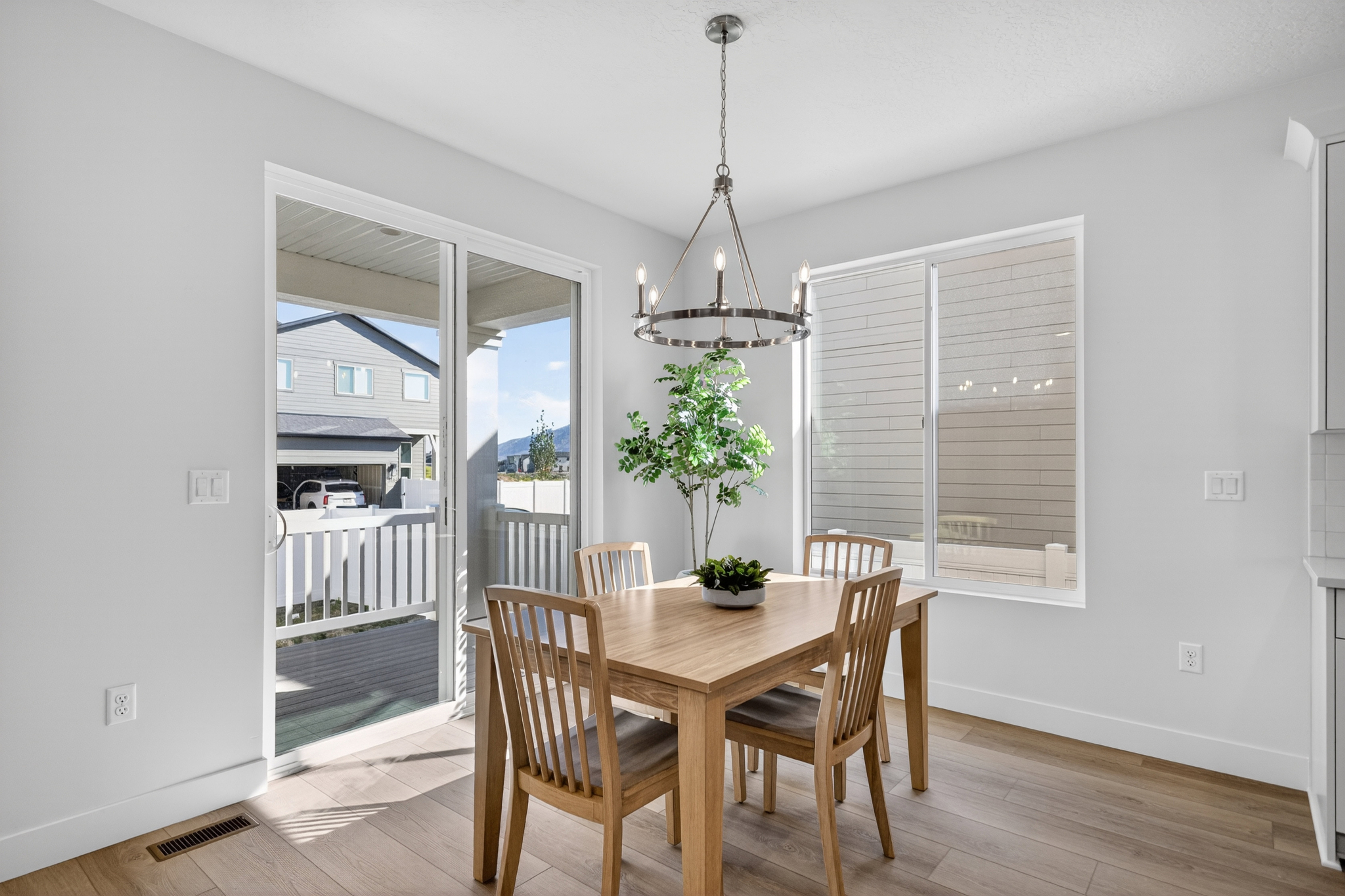 Dining area featuring wood-finish flooring, a contemporary chandelier, and ample natural light from the sliding glass door and window