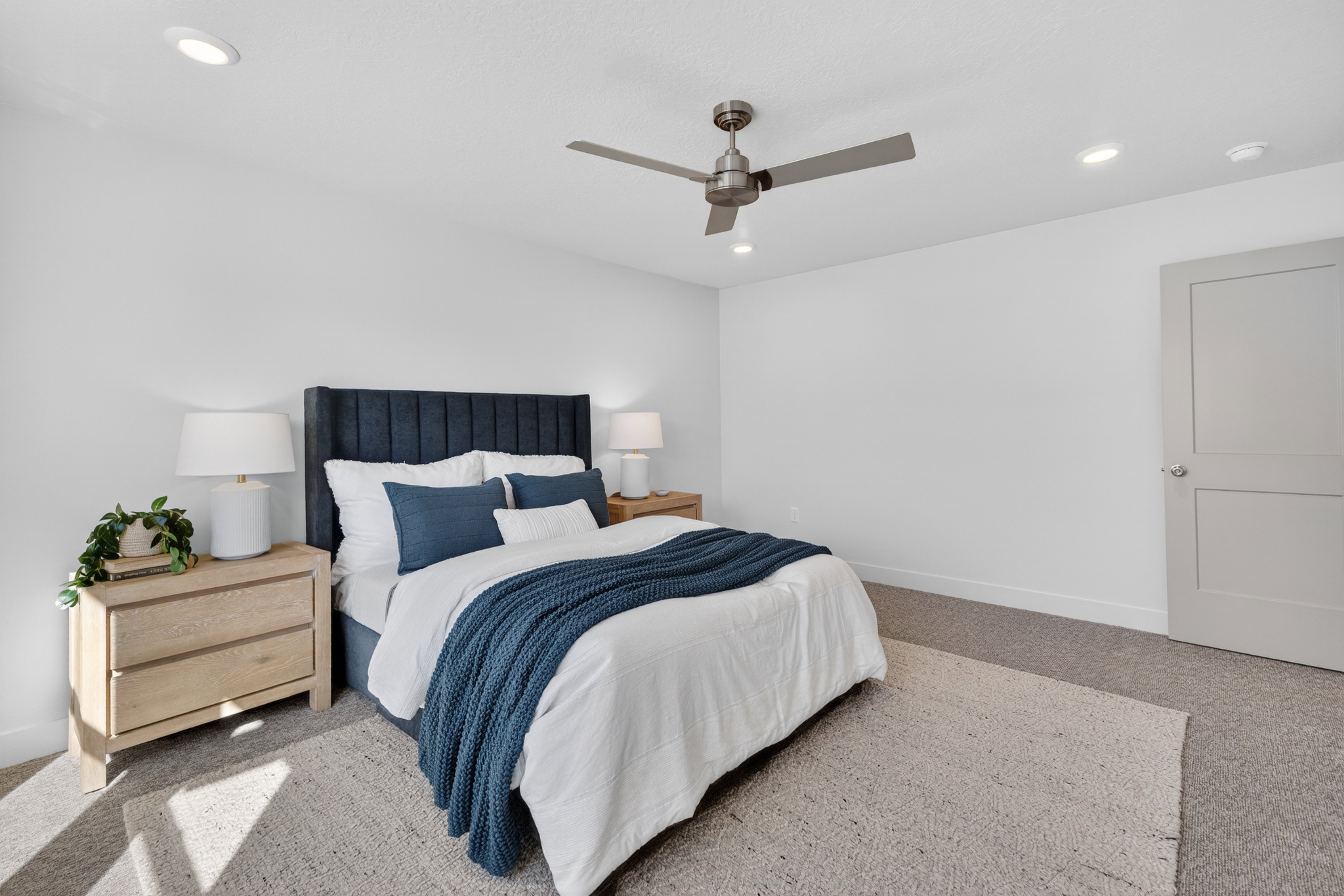 Carpeted room featuring a ceiling fan with integrated lighting, recessed ceiling lighting, and a neutral painted door