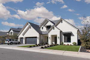 Modern farmhouse style home with a front yard, brick siding, driveway, and a garage