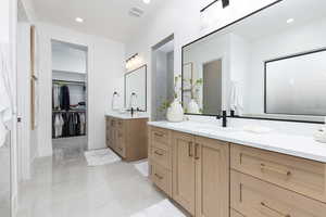 Bathroom featuring a walk in closet, two vanities, and recessed lighting