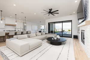 Living room featuring light wood-style flooring, a ceiling fan, a fireplace, and recessed lighting