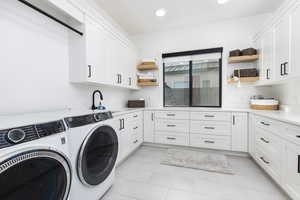 Laundry area with cabinet space, washer and dryer, recessed lighting, and light tile patterned floors