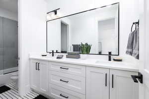 Bathroom featuring double vanity and shower / bath combination with glass door