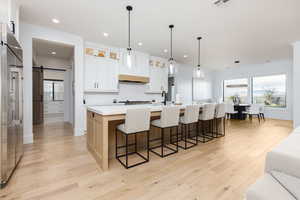 Kitchen featuring a barn door, glass insert cabinets, a breakfast bar area, a large island, and light wood-style floors