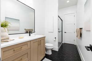 Full bath with a shower stall, vanity, dark tile patterned flooring, and recessed lighting