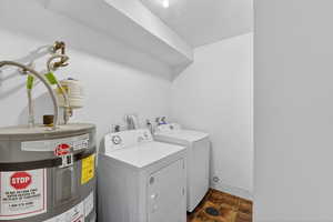 Laundry room featuring water heater, washing machine and dryer, and a textured ceiling