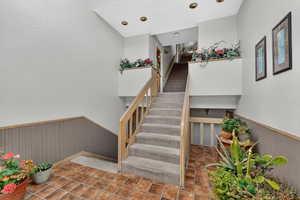 Staircase with wainscoting, a textured wall, and wood walls