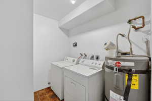 Laundry room featuring strapped water heater, and tile patterned floors