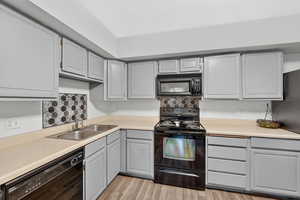Kitchen featuring black appliances, gray cabinets, and light countertops