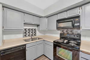 Kitchen with black appliances, light countertops, and gray cabinetry
