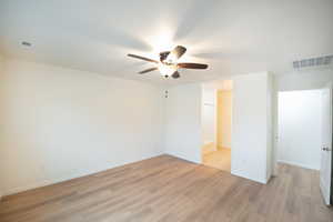 Unfurnished bedroom with light wood-type flooring, ceiling fan, and ensuite bathroom