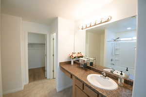 Full bathroom with vanity,  shower combination, a spacious closet, and light tile patterned floors