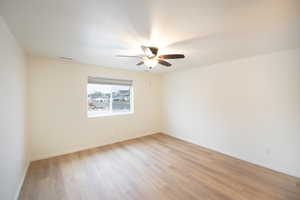 Empty room with light wood finished floors and a ceiling fan