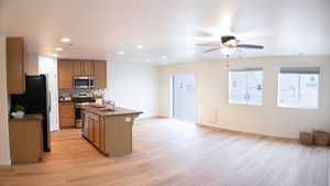Kitchen with recessed lighting, stainless steel appliances, light wood-type flooring, open floor plan, and ceiling fan