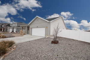 View of front of home with board and batten siding, concrete driveway, an attached garage, and a porch