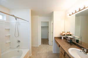 Bathroom with vanity, a walk in closet, bathtub / shower combination, and light tile patterned floors