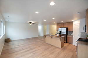 Kitchen featuring a breakfast bar, a kitchen island with sink, open floor plan, stainless steel appliances, and recessed lighting