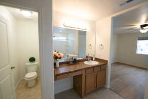 Full bath with vanity, a shower with door, a ceiling fan, and light tile patterned flooring