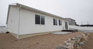 Rear view of house with a deck, a gate, and stucco siding