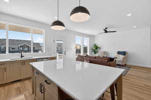 Kitchen with a kitchen island, tasteful backsplash, hanging light fixtures, open floor plan, and light wood finished floors