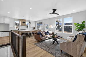 Living area featuring light wood-style floors, ceiling fan, and recessed lighting