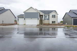 View of front of house with stone siding, board and batten siding, a shingled roof, and concrete driveway