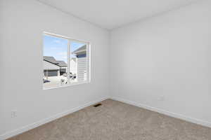 Spare room featuring baseboards and carpet floors