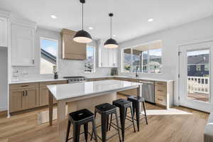Kitchen featuring backsplash, dual tone cabinetry, a center island, a kitchen breakfast bar, and light wood-type flooring