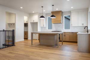 Two tone kitchen with two tone cabinetry, backsplash, stainless steel appliances, decorative light fixtures, and a kitchen bar