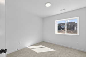 Unfurnished room featuring baseboards and light carpet