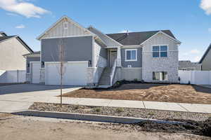 View of front facade with board and batten siding, stone siding, driveway, a shingled roof, and an attached garage