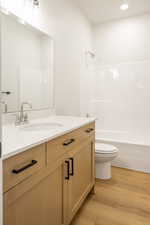 Full bathroom featuring vanity, light wood-style floors, shower / tub combination, and recessed lighting