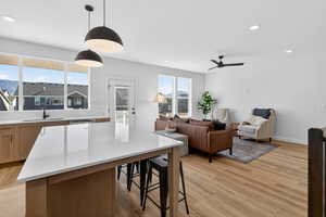 Kitchen with a kitchen breakfast bar, light wood-type flooring, pendant lighting, open floor plan, and a kitchen island