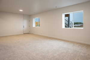 Empty room with light colored carpet and recessed lighting
