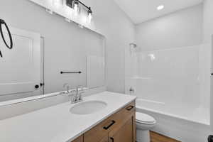 Bathroom with vanity, shower / tub combination, light wood finished floors, and recessed lighting