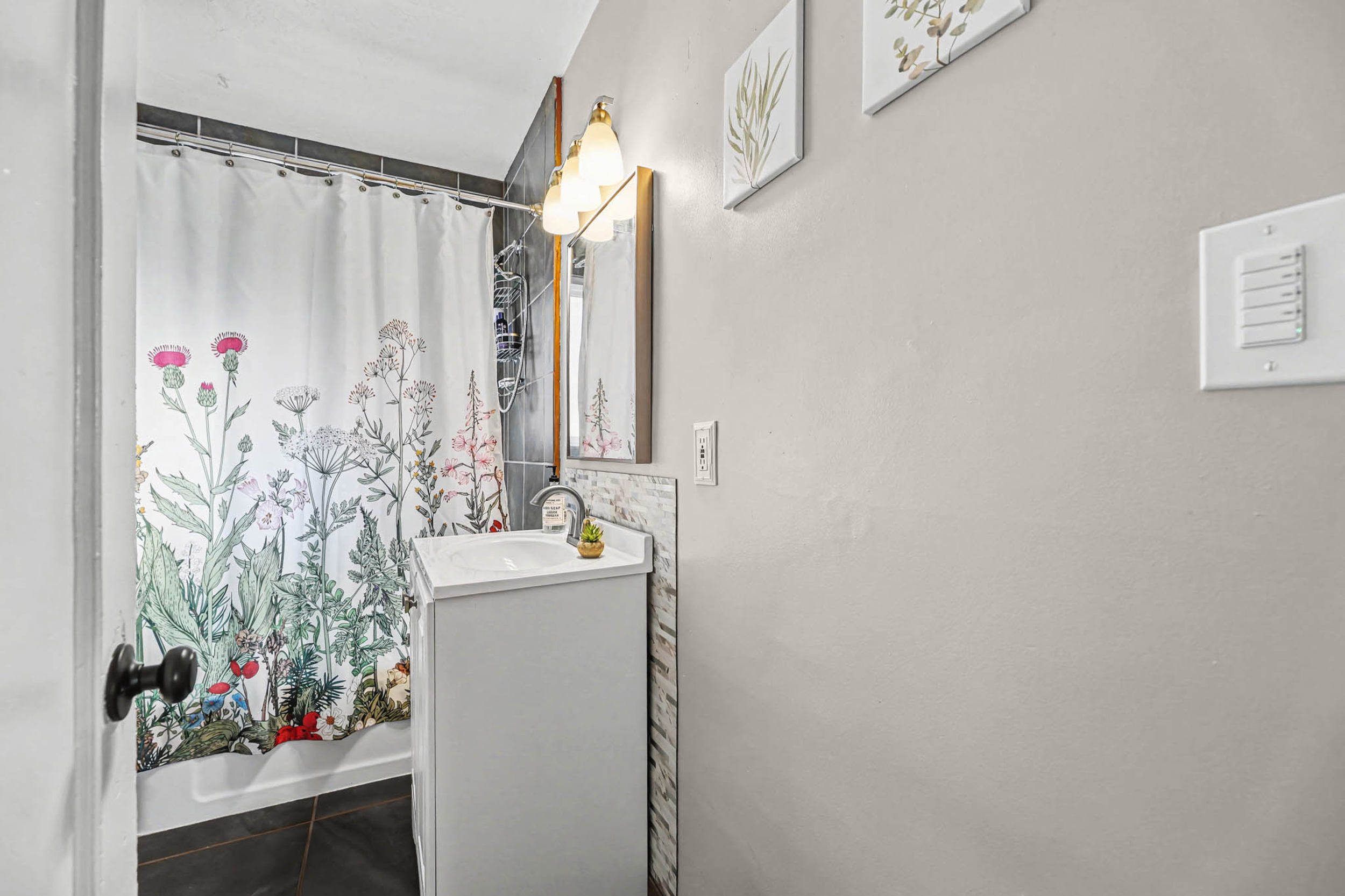 Bathroom with vanity, shower / tub combo, and dark tile patterned flooring