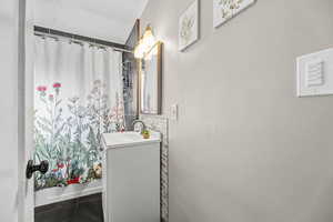Bathroom with vanity, shower / tub combo, and dark tile patterned flooring