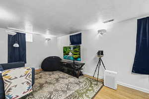 Recreation room with a textured ceiling and wood finished floors