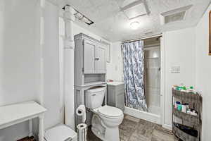 Full bathroom with a shower stall, a textured ceiling, and dark stone finish flooring