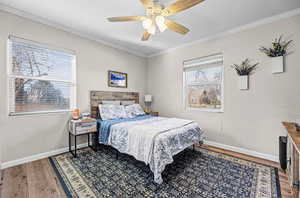 Bedroom with wood finished floors, ceiling fan, crown molding, and a textured wall