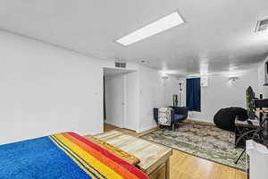 Bedroom with a textured ceiling and light wood finished floors