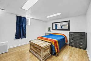 Bedroom with light wood-style floors and a textured ceiling