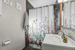 Full bath with vanity and dark tile patterned floors