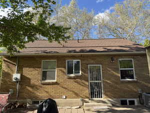 Back of house with a patio, roof with shingles, and brick siding