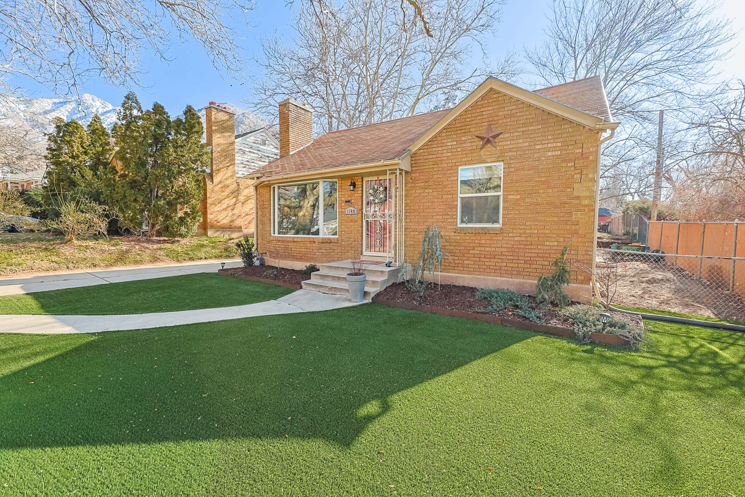 Bungalow-style home with a chimney and brick siding
