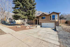 Split foyer home with stone siding, stucco siding, an attached garage, and concrete driveway