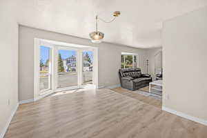 Living area with light wood-style floors and a textured ceiling