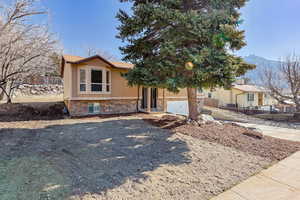 Split foyer home featuring stone siding, stucco siding, and a mountain view