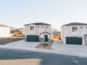 Modern farmhouse featuring a garage, stucco siding, stone siding, and concrete driveway